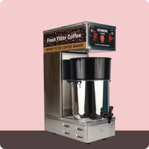 A stainless steel Gemini classic filter coffee maker with a large black handled pot and spout, set against a pink and gray background.